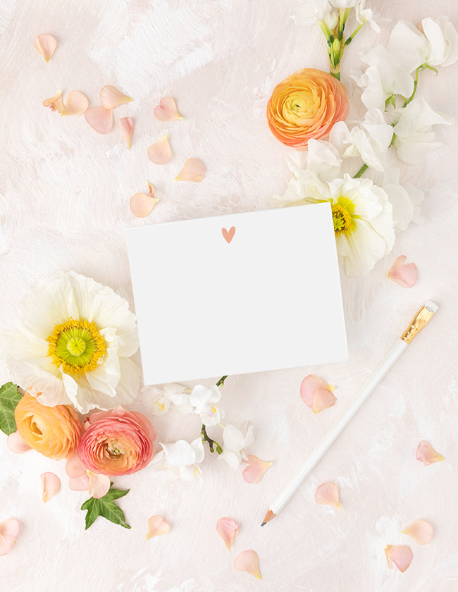 Flat note card with a heart design and pen on a floral background