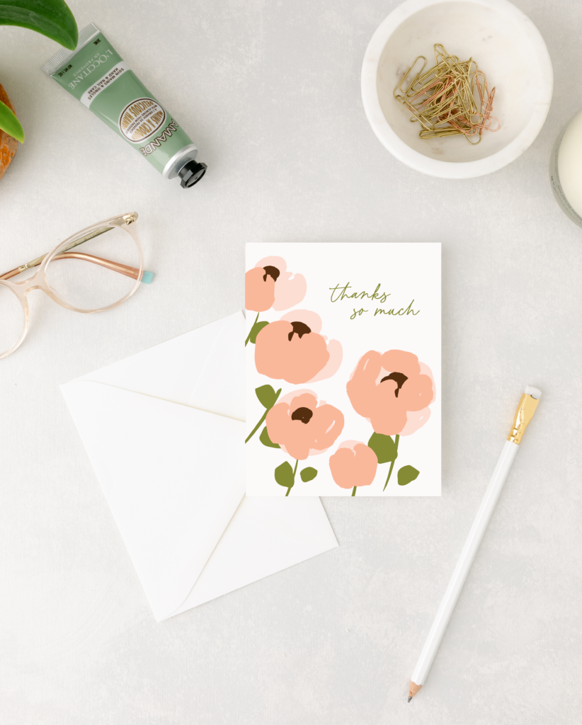 Floral card with 'Thanks so much' text on a white surface with stationery items.